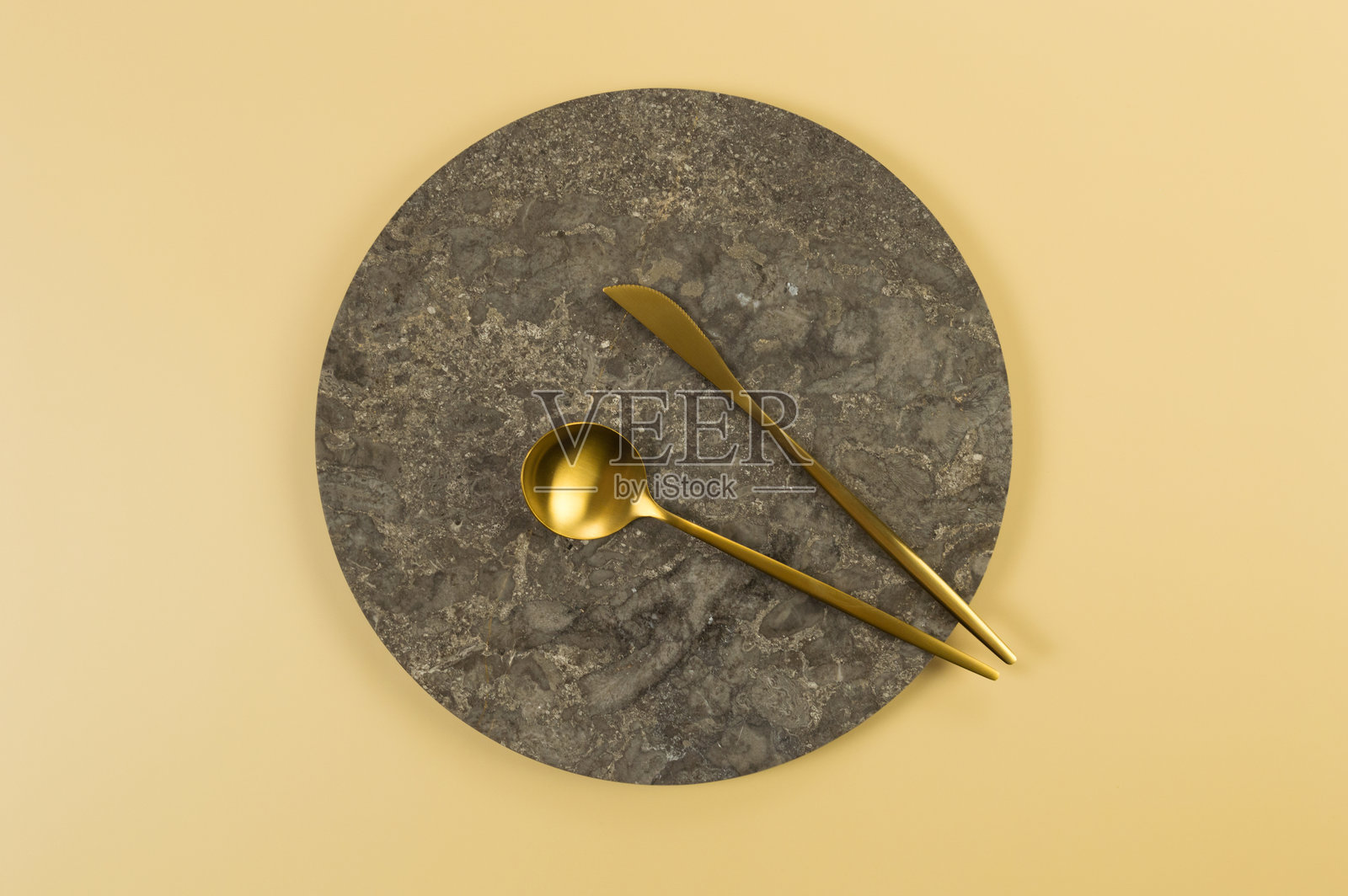 棕色大理石盘的俯视图,金色餐具放在黄色背景上。食物展示,石制托盘。照片摄影图片