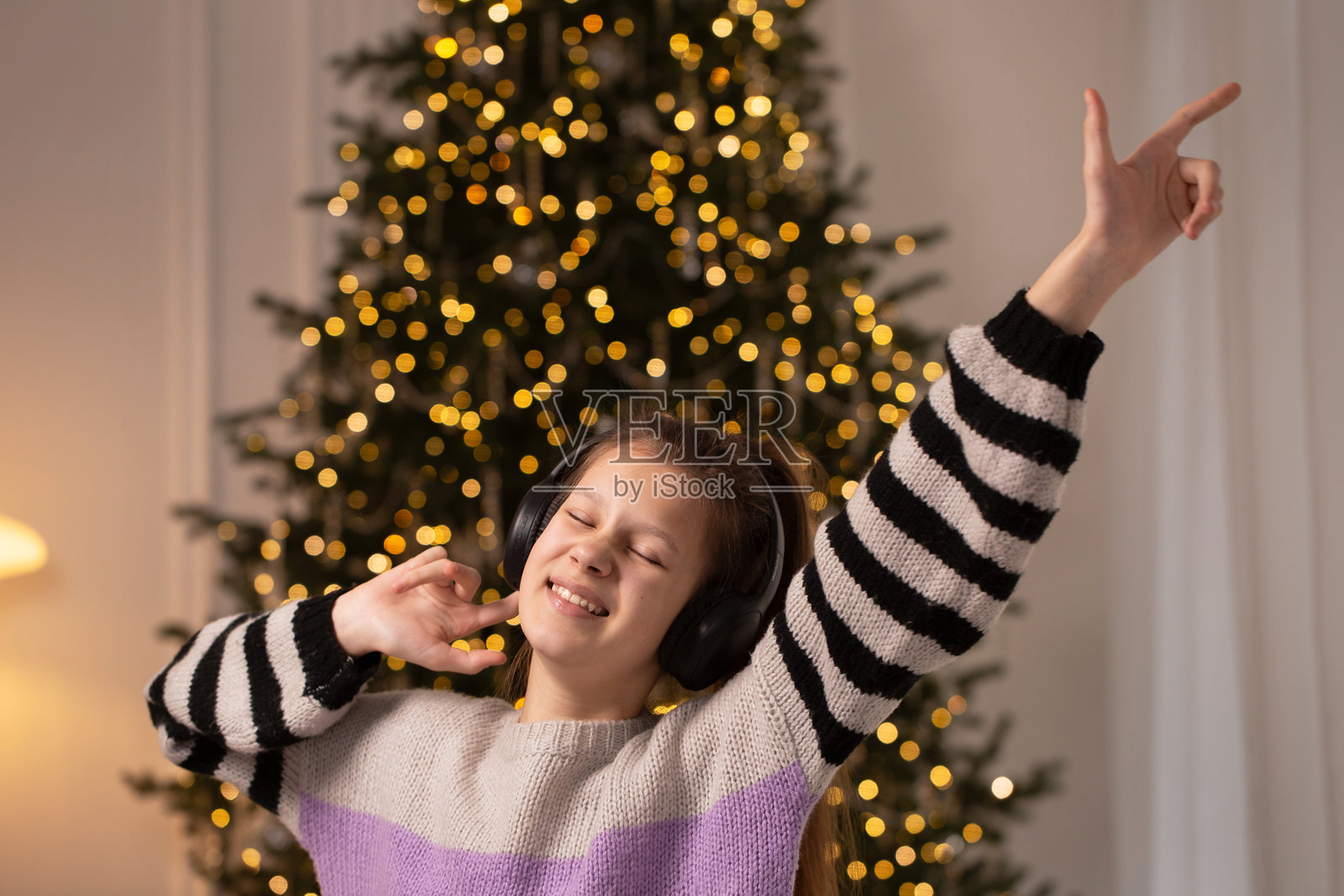 一个女孩在圣诞树前跳舞唱歌照片摄影图片