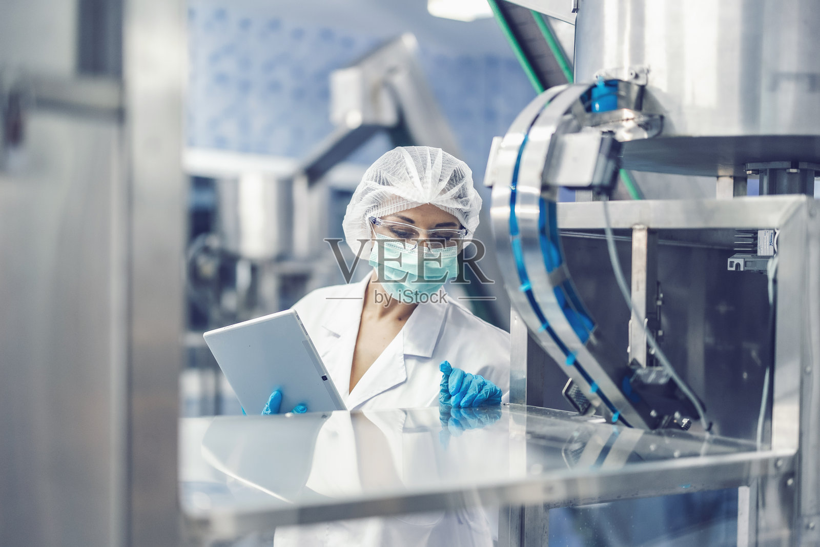 女性卫生工作者在科学实验室工作。制药生产机器检查员。照片摄影图片