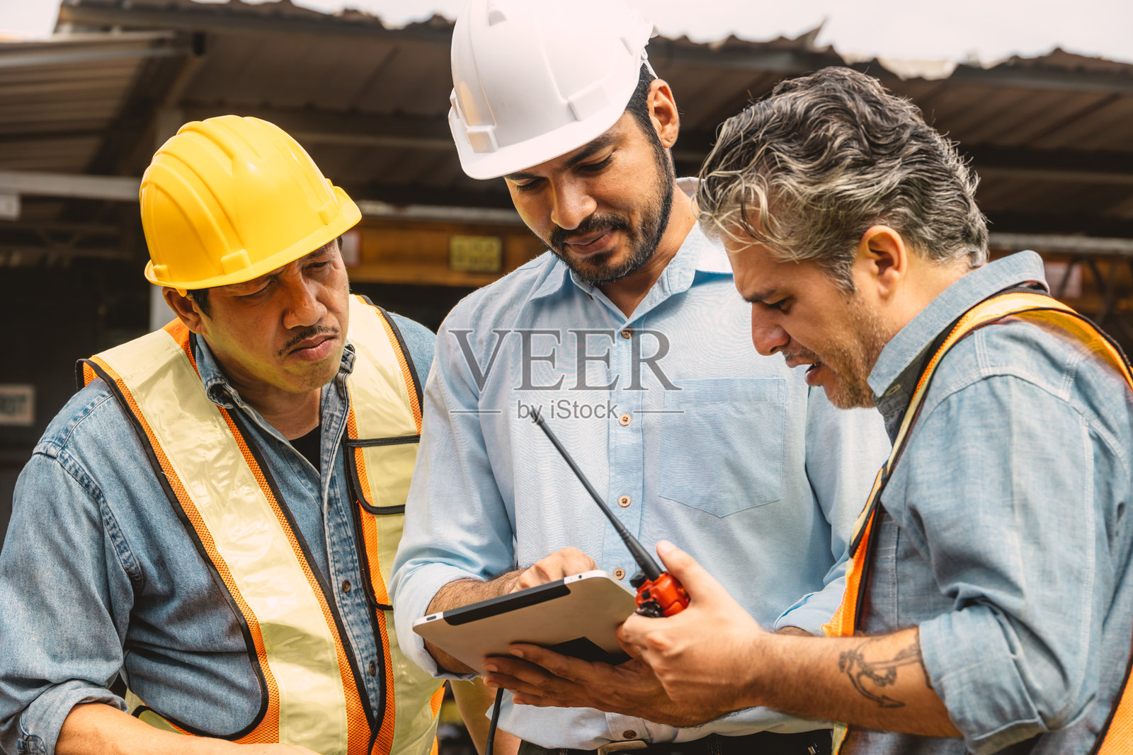 专业建筑工程师团队在施工现场合作,共同咨询,查看平板电脑上的项目。照片摄影图片