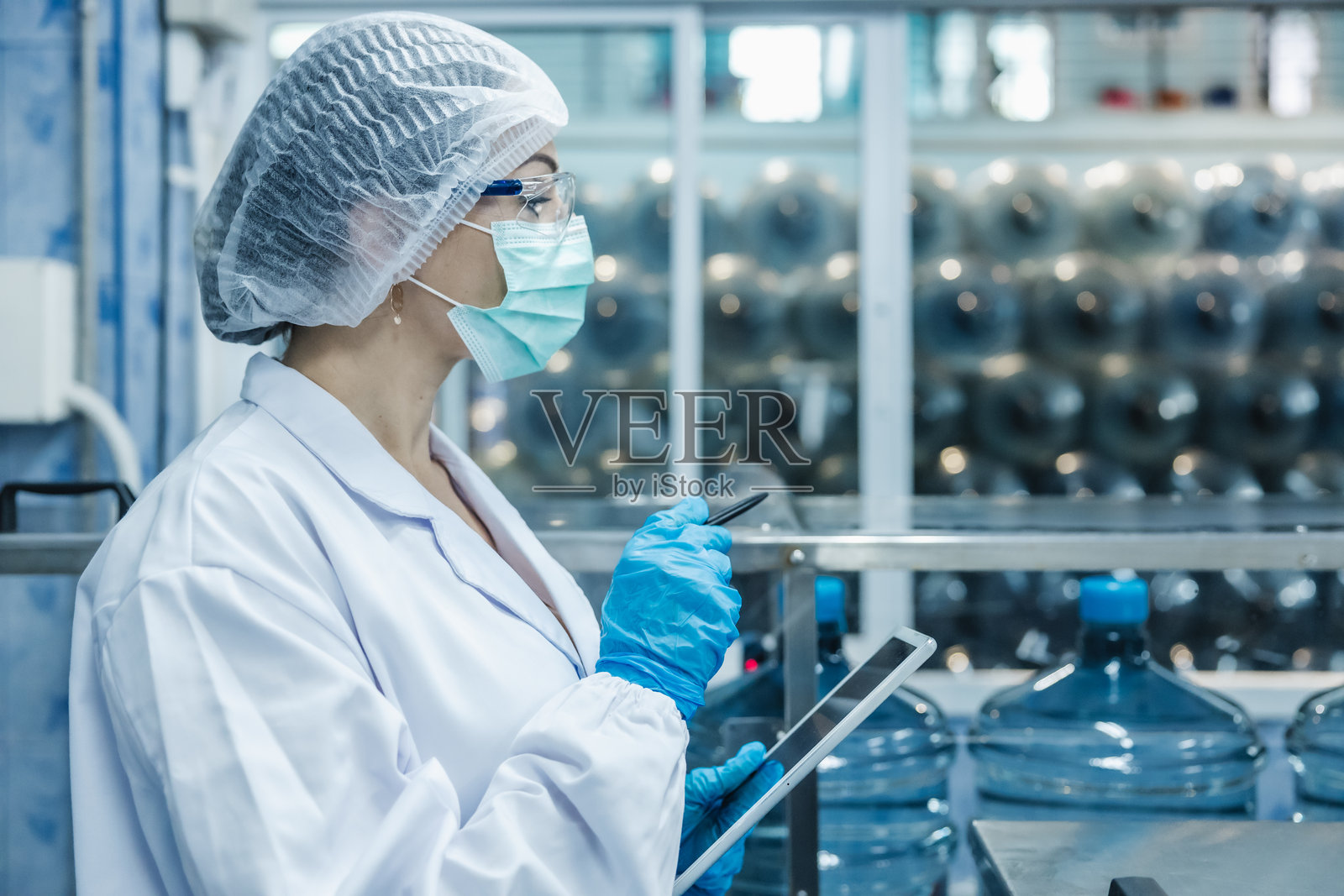 在饮用水工厂工作的工人,穿着卫生制服,保持工作场所的清洁与卫生。照片摄影图片