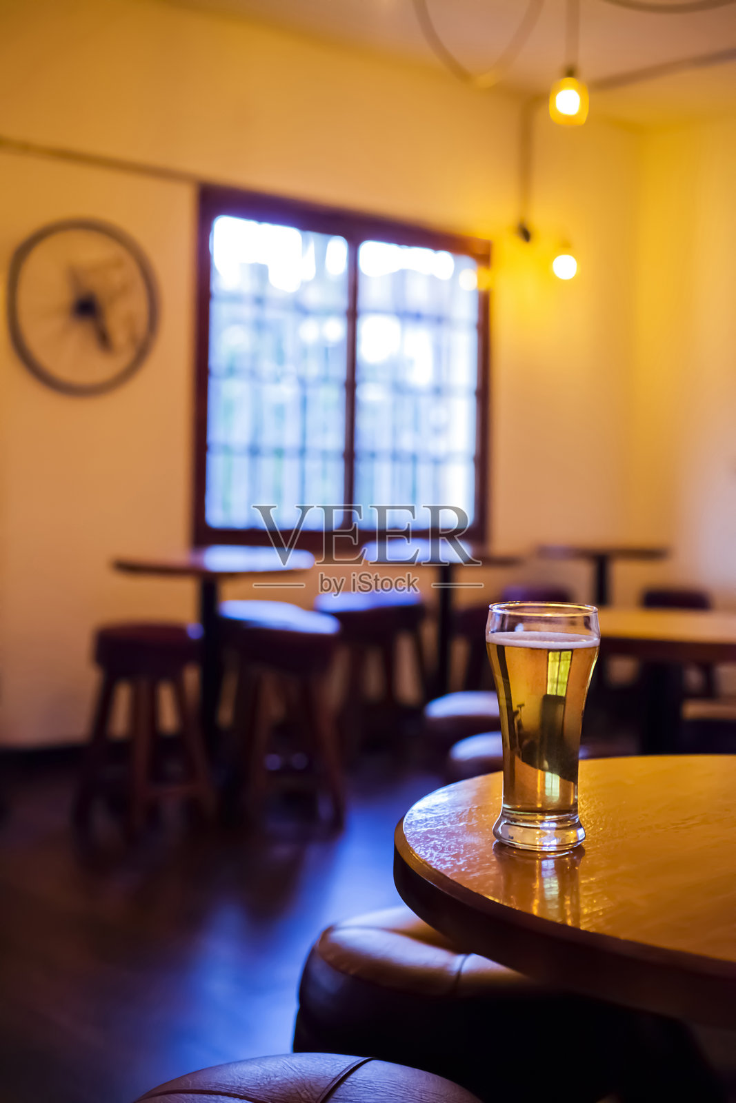 温暖昏暗酒吧木桌上的一杯啤酒照片摄影图片