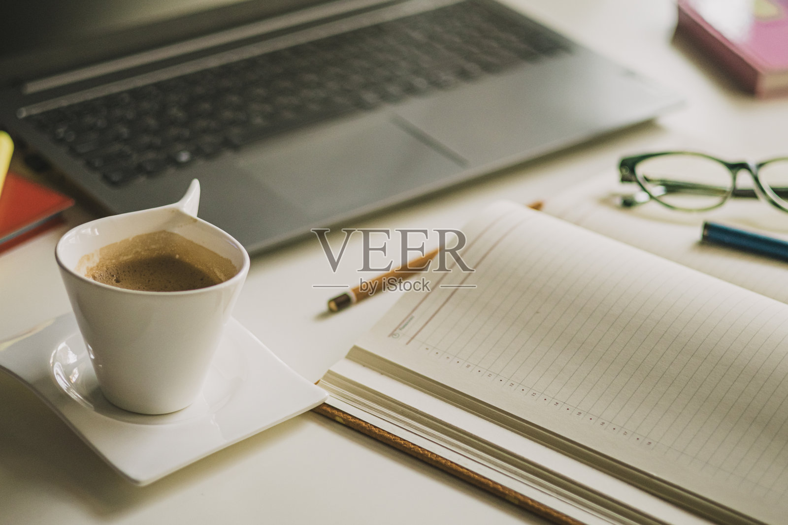 女性办公室桌子。笔记本电脑、咖啡杯、阅读眼镜和办公用品。照片摄影图片