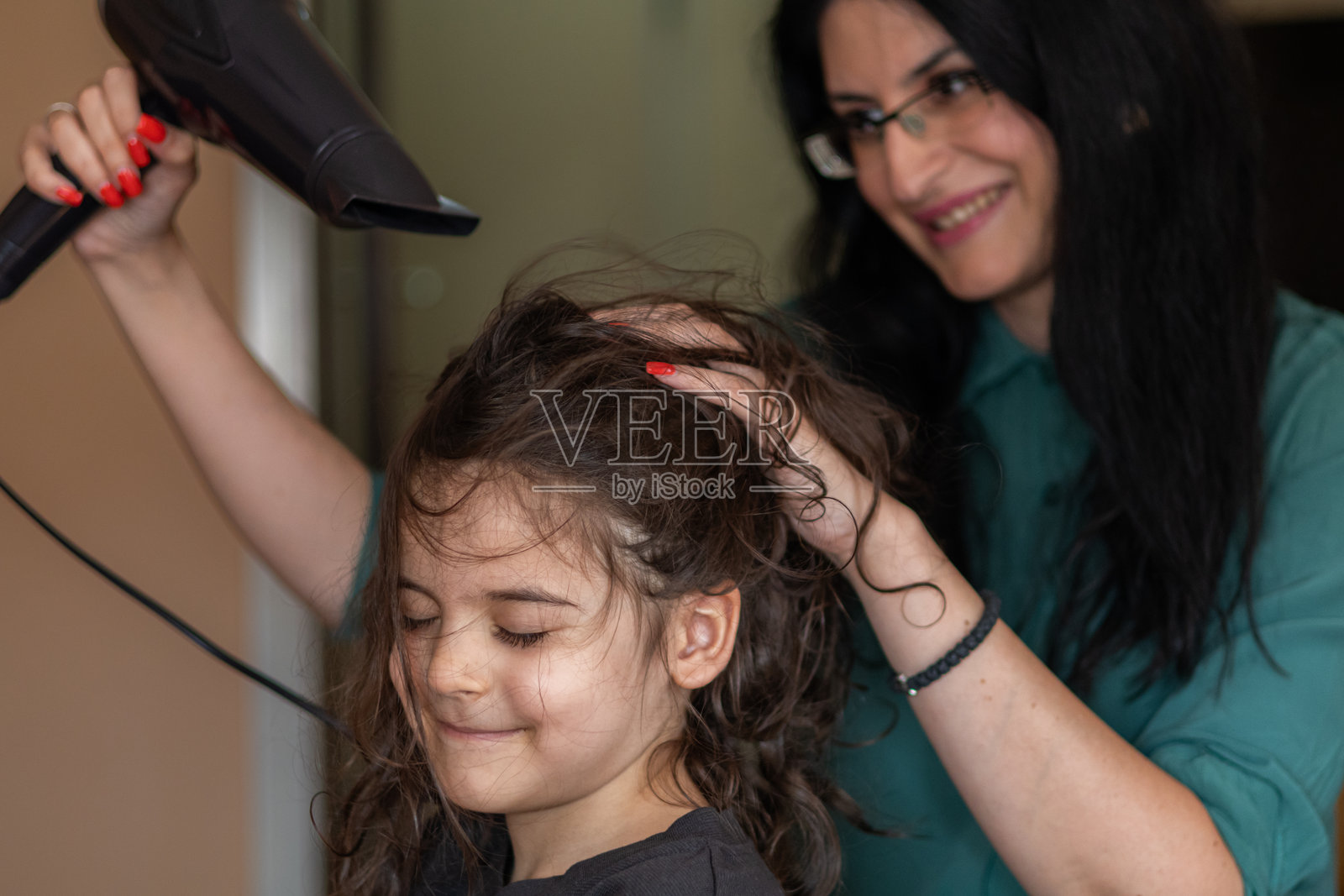 母亲和儿子在家客厅里梳理和吹干头发的亲密、快乐、顽皮时刻。照片摄影图片