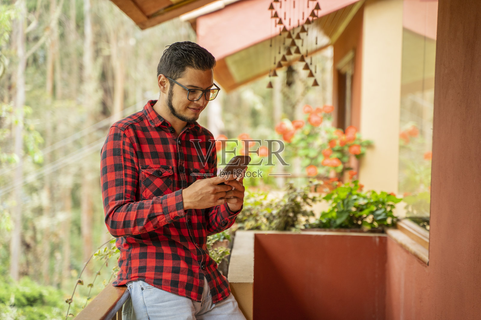 男子在房子的阳台上查看手机照片摄影图片