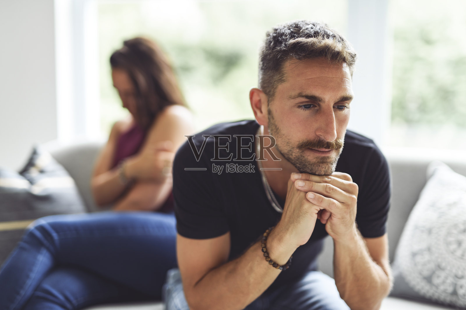 在家客厅的沙发上,一对情侣因出轨或分手而争吵,显得不快乐、沮丧或伤心。照片摄影图片