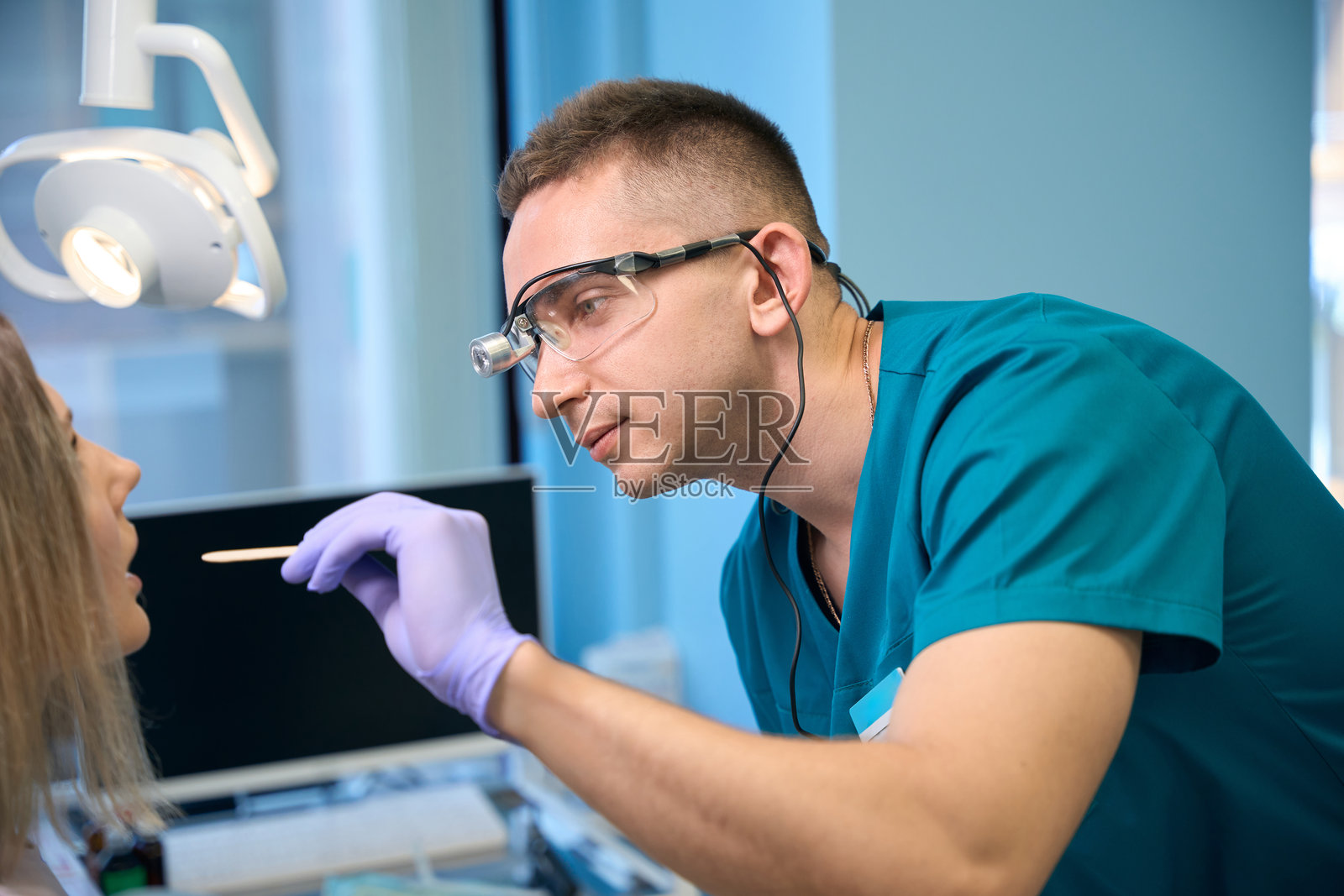 耳鼻喉科医生使用检查舌压器检查年轻女性的喉咙照片摄影图片