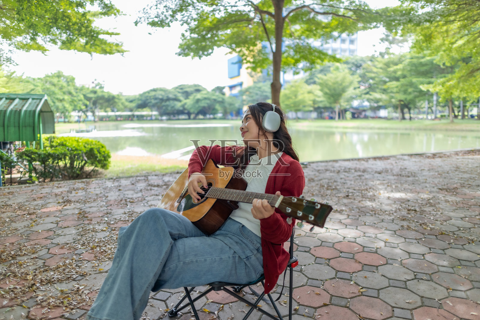 年轻女性在宁静的户外公共空间弹奏原声吉他,营造出平静而艺术的氛围照片摄影图片