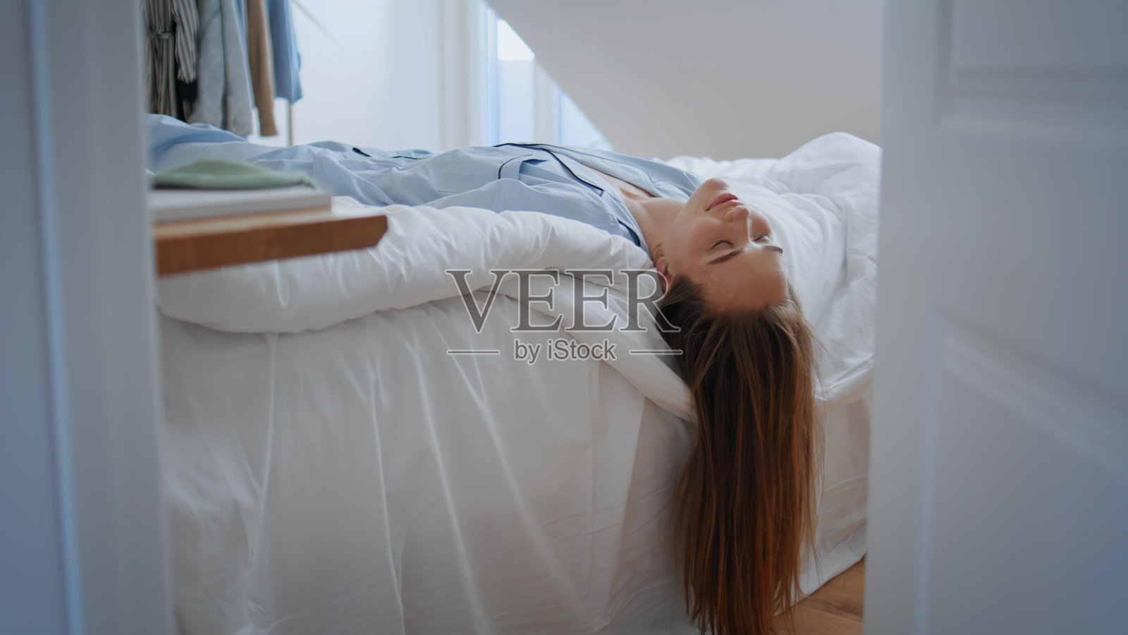 困倦的模特在床上醒来特写。睡意朦胧的女人躺在枕头上,头发轻触。照片摄影图片