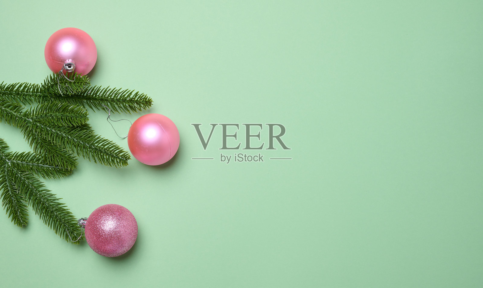 闪亮的粉色球和绿色的松枝在绿色背景上,圣诞背景照片摄影图片