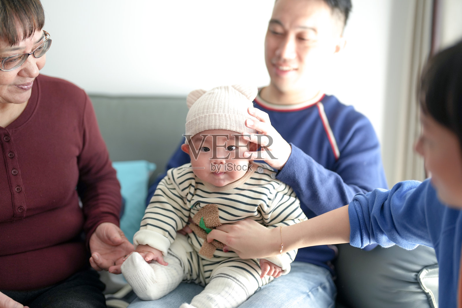 一个6个月大的男孩穿着圣诞服装,在寒冷的冬天与他的父亲、母亲和祖母一起在上海浦东新区的室内度过时光。照片摄影图片