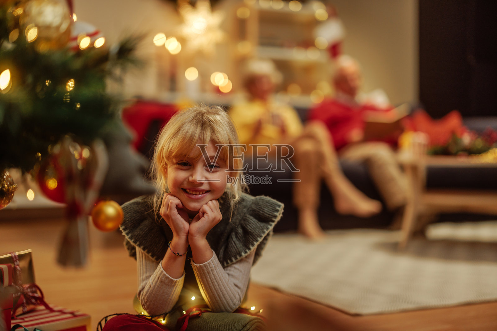 可爱的小女孩在圣诞树前包装圣诞礼物,并对着镜头微笑照片摄影图片