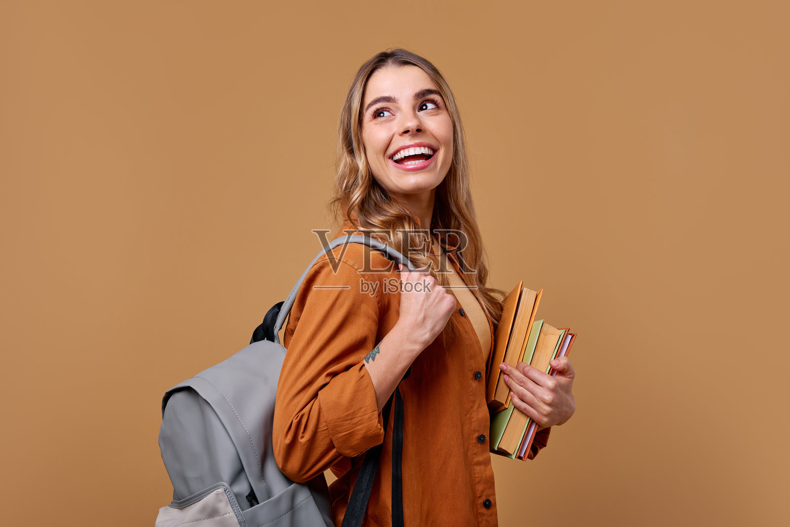 一个穿着休闲服装、愉快地享受生活的学生,手里拿着书籍。照片摄影图片