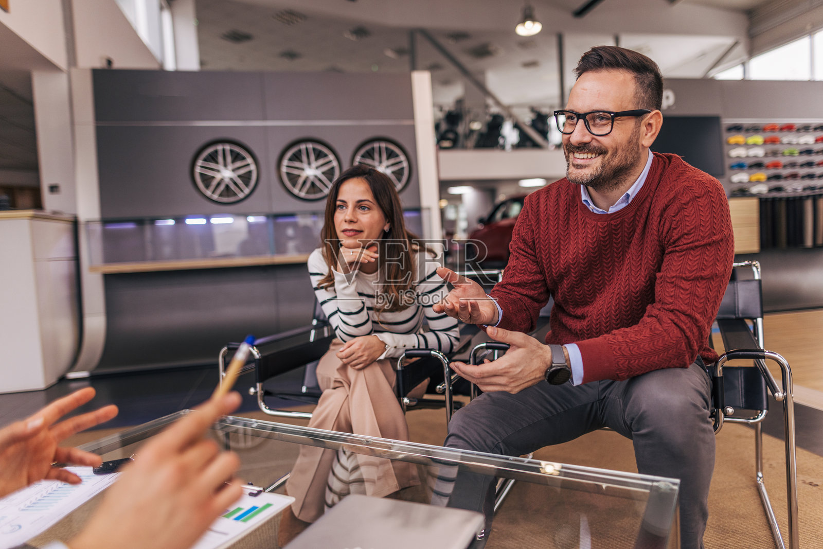 快乐的情侣在展厅与汽车销售员达成了协议。照片摄影图片