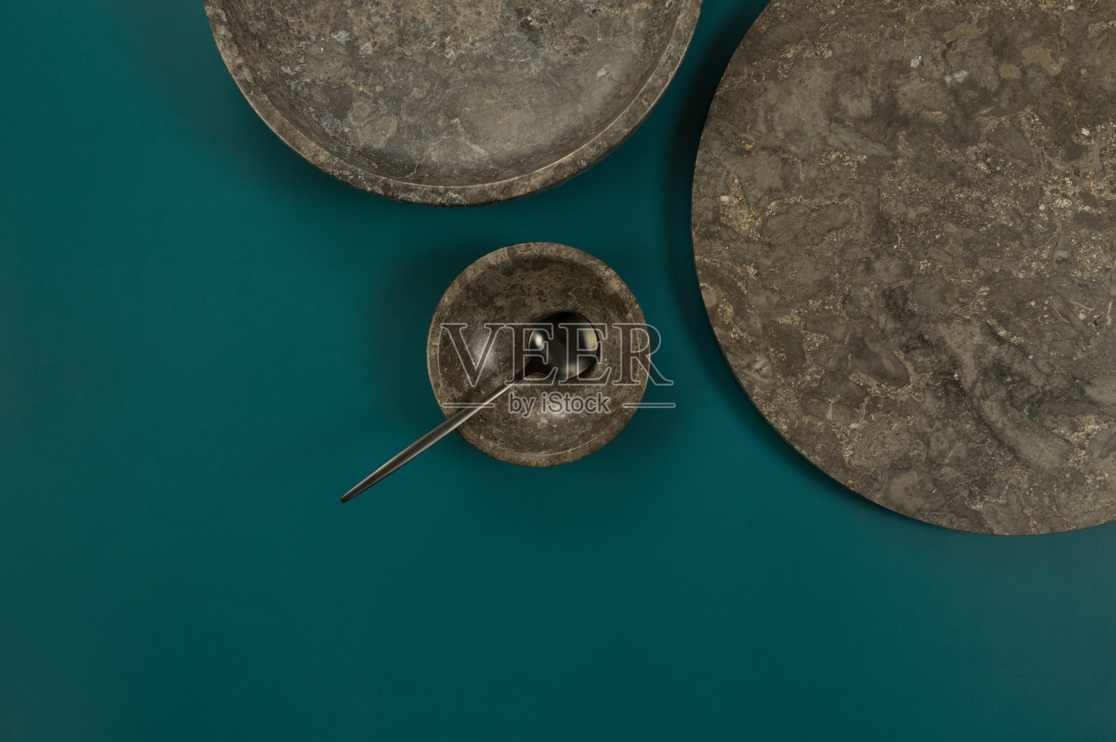 棕色大理石托盘、盘子、碗和黑色餐具在深绿色背景上的俯视图。食品展示,餐具,石材托盘。照片摄影图片