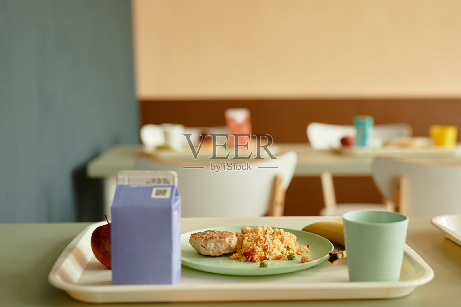 学校食堂餐桌上的托盘,盛着小米饭和切好的肉块午餐照片摄影图片