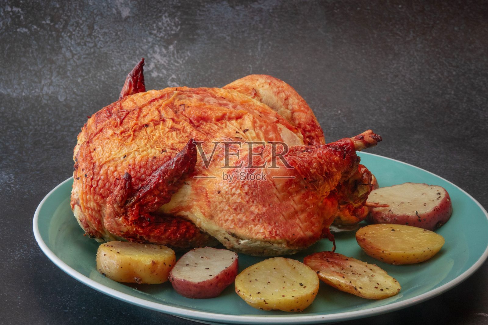 蓝色盘子上的烤鸡和调味土豆。照片摄影图片