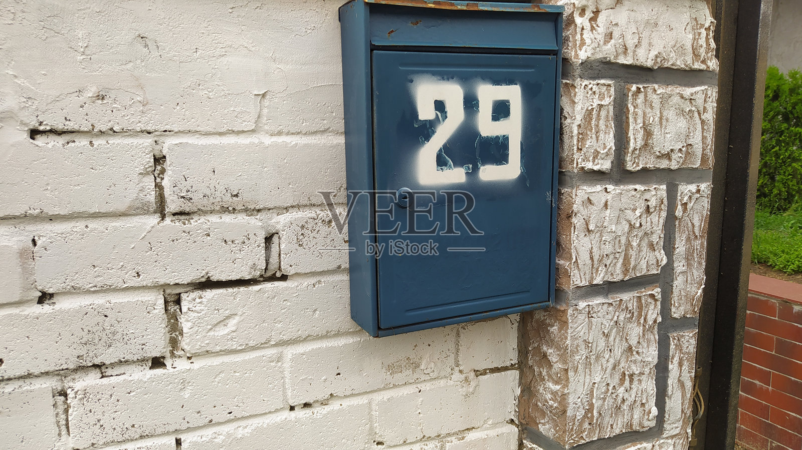一个迷人的蓝色邮箱,编号29优雅地固定在经典的砖墙上照片摄影图片