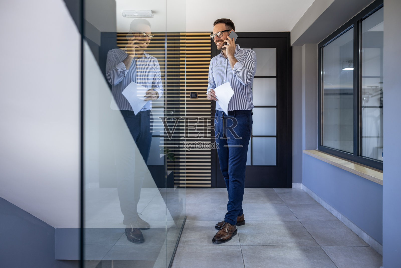 现代办公室走廊中打电话的商人照片摄影图片