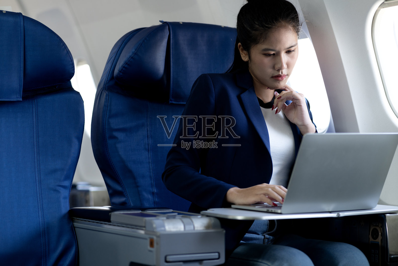 年轻女性在飞机上舒适地使用笔记本电脑照片摄影图片