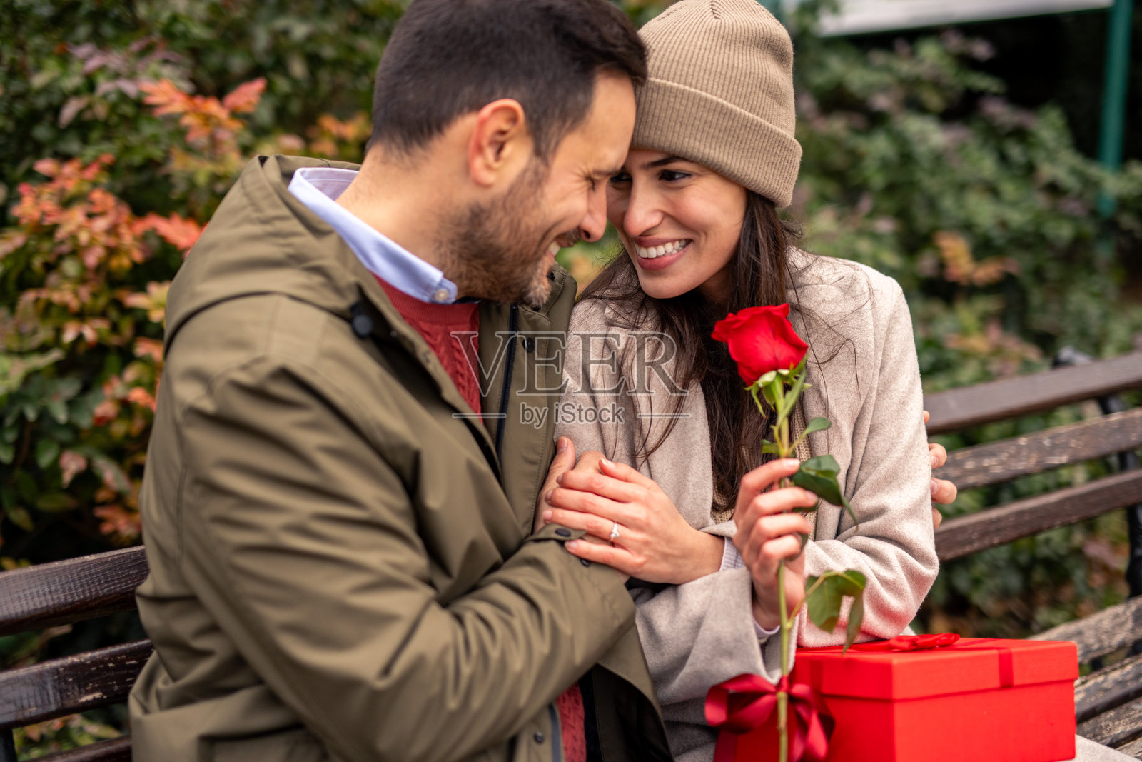 快乐的白人男性在公园里给女性惊喜送礼照片摄影图片