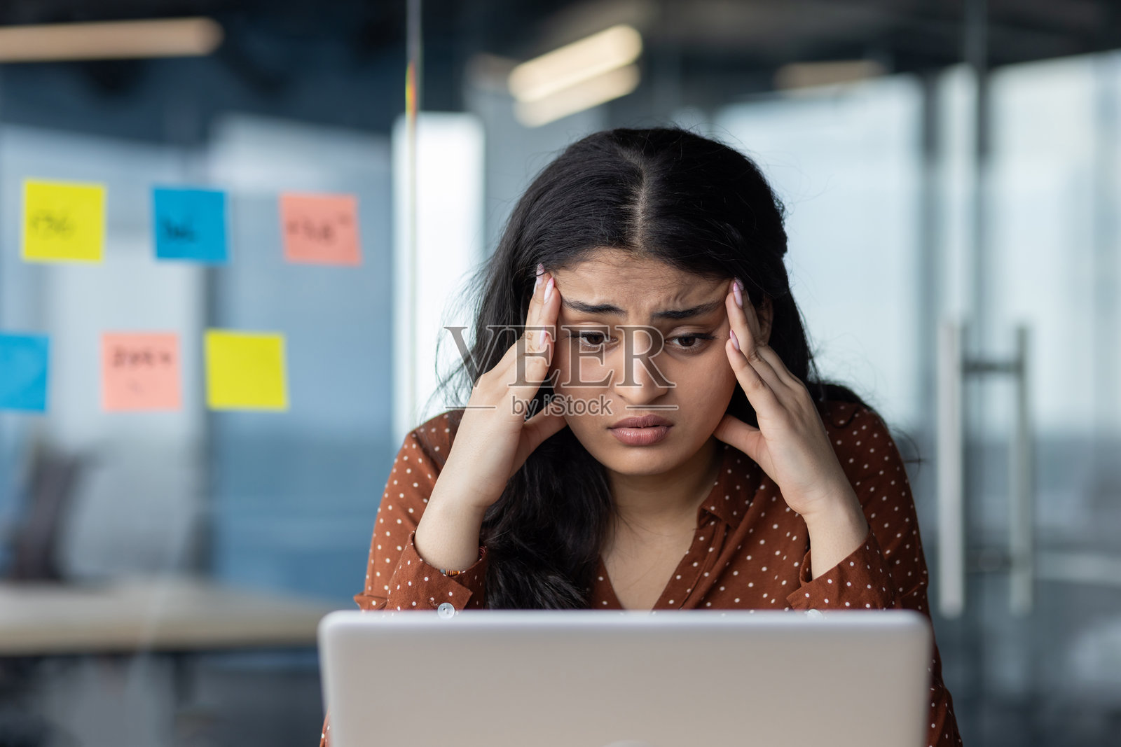 在办公室里忙于笔记本电脑工作的年轻西班牙裔女商人感到压力。她在工作中感到沮丧和不堪重负。过度工作的员工在现代职场中承受压力管理压力。照片摄影图片