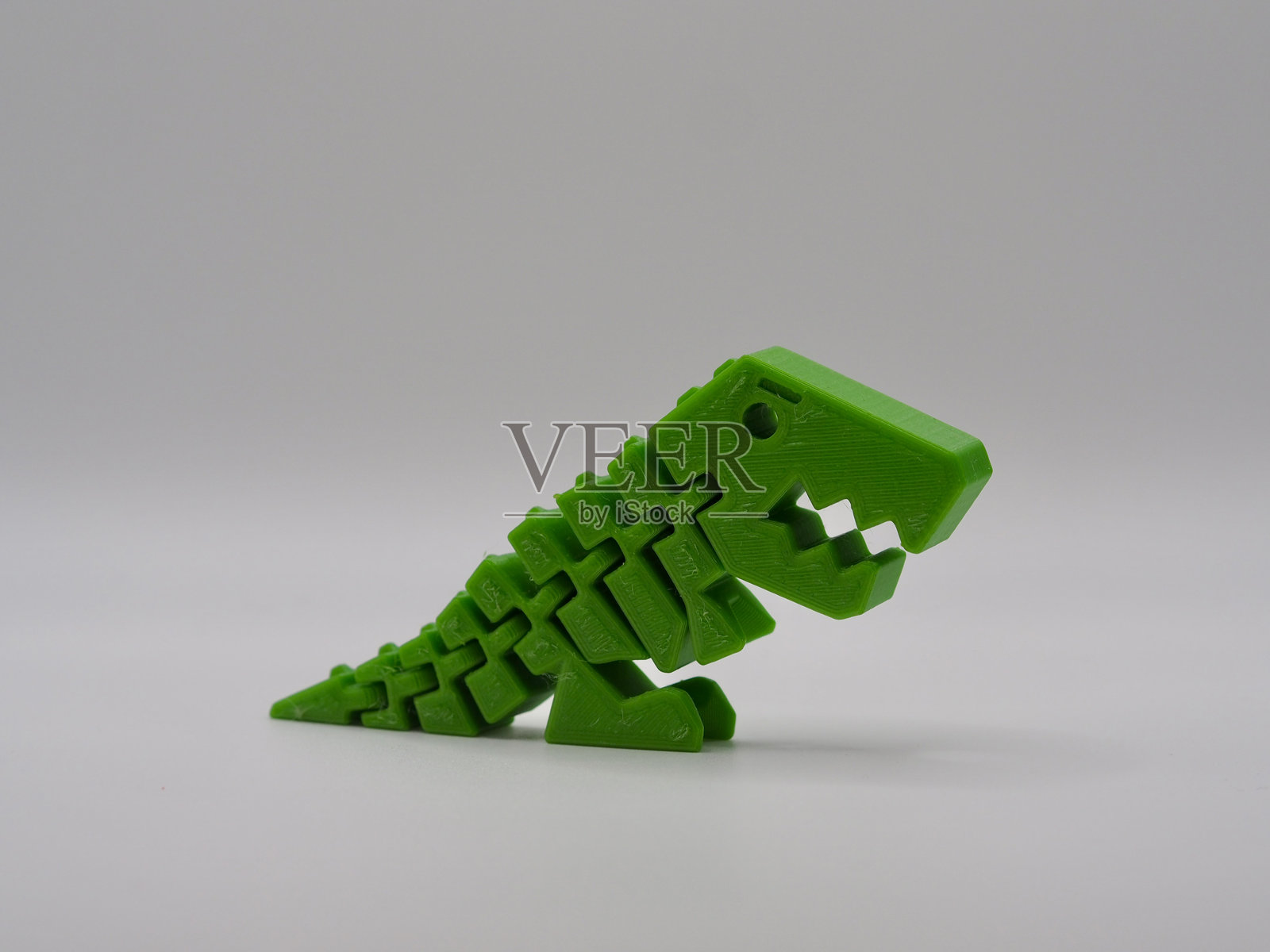 这张图片展示了一款生动的绿色3D打印恐龙玩具,摆出俏皮而动感的姿势,体现了创意和现代打印技术的创新。照片摄影图片