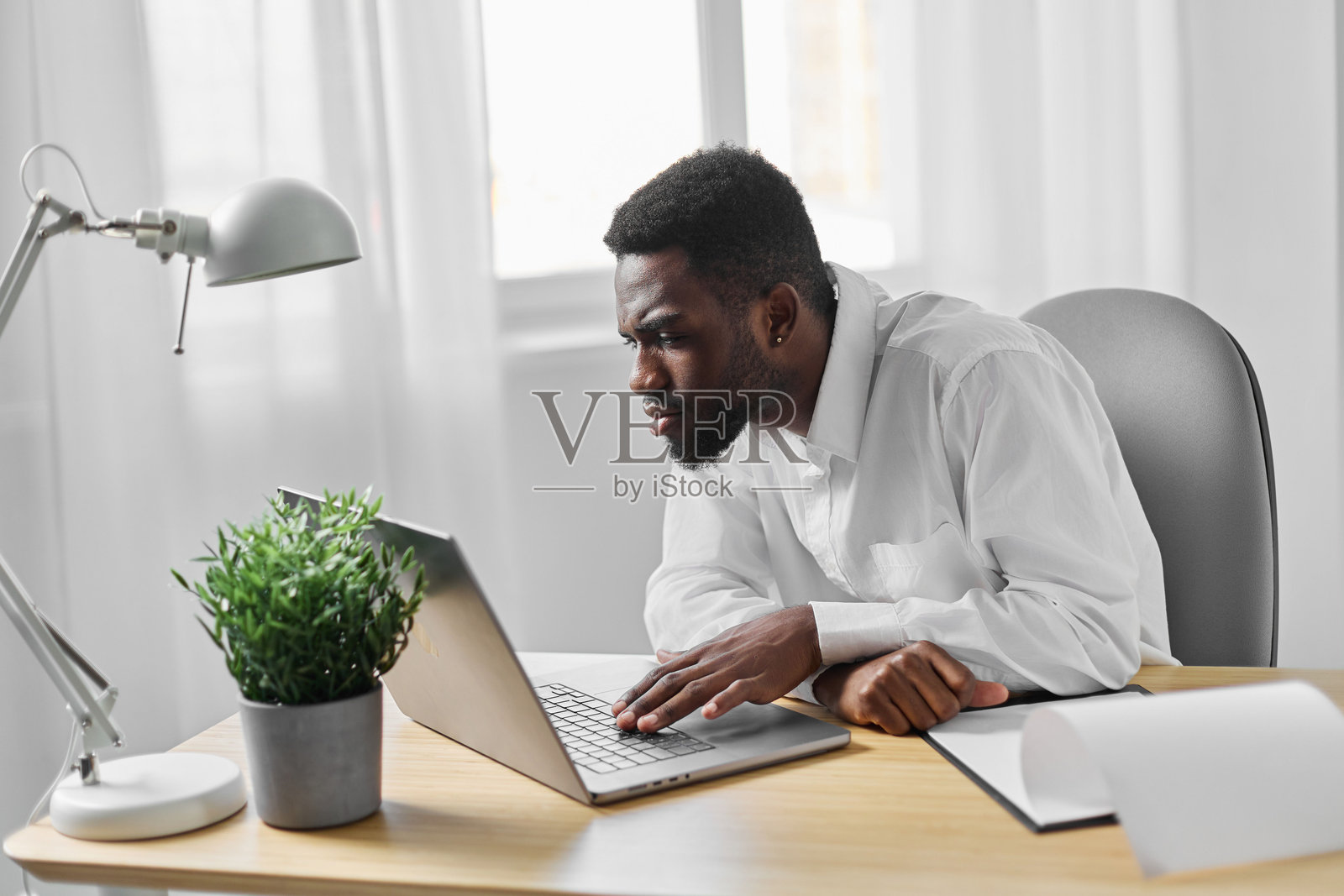 非洲男子在办公室使用笔记本电脑进行在线自由职业工作,学生教育。照片摄影图片