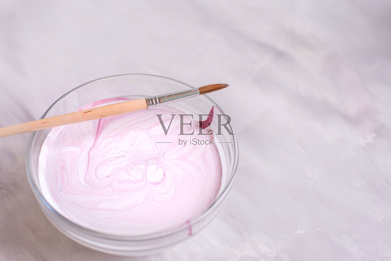 不同颜色的颜料放在玻璃容器中,旁边有画笔,背景为浅色。留有空白空间。照片摄影图片