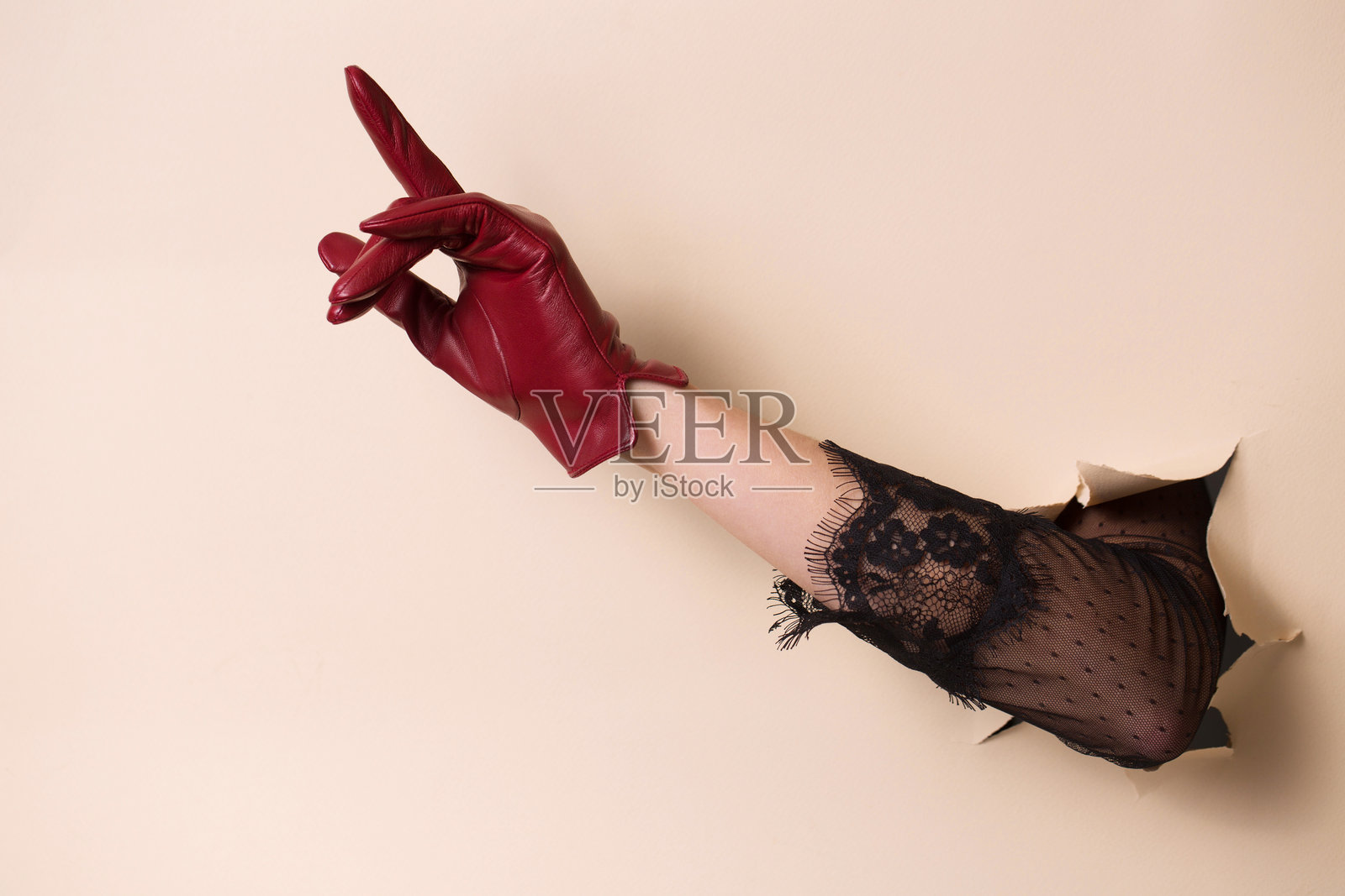 一只戴着皮手套的女人的手用食指指着。照片摄影图片