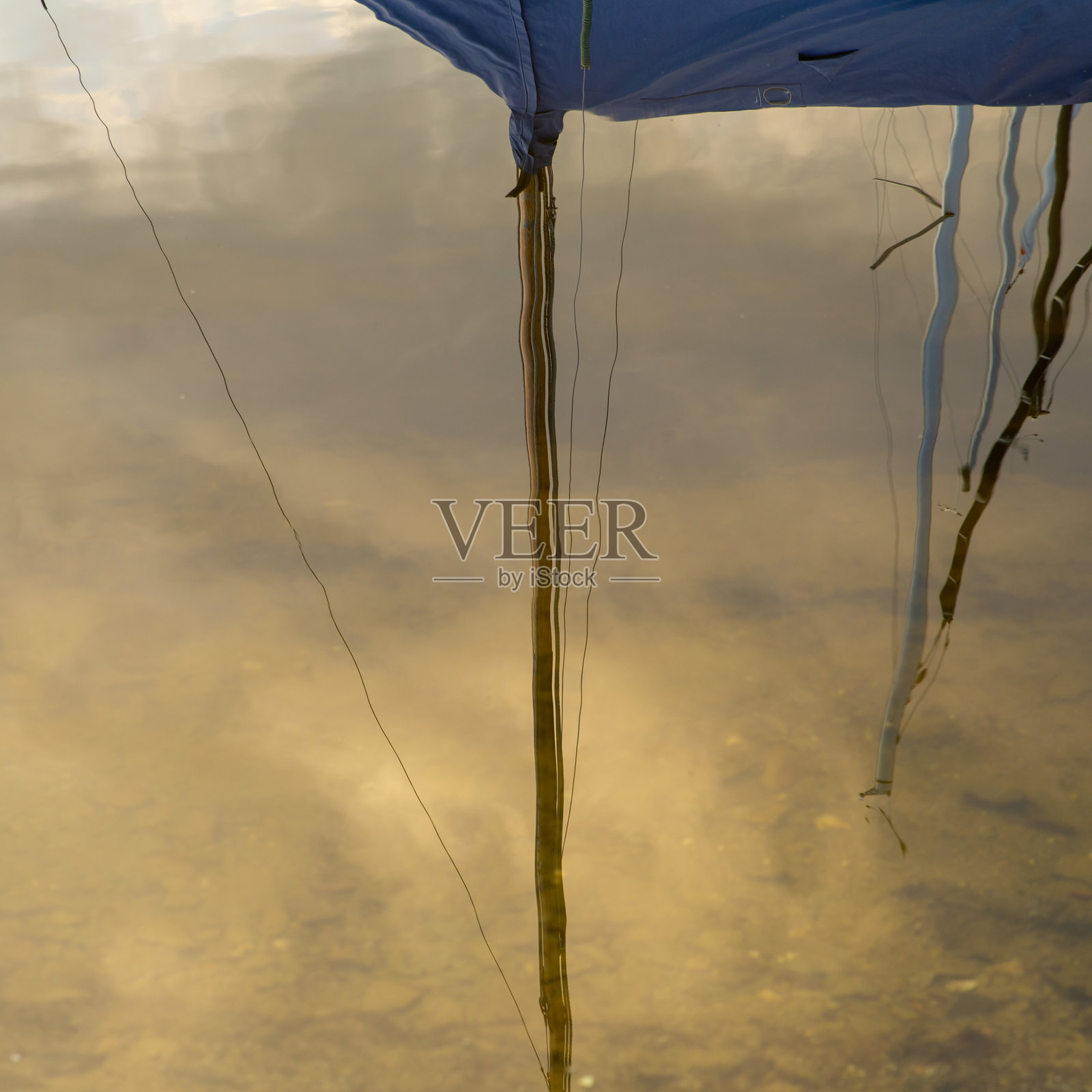 帆船桅杆在水中的倒影,带有黄色调,梦幻般的感觉照片摄影图片