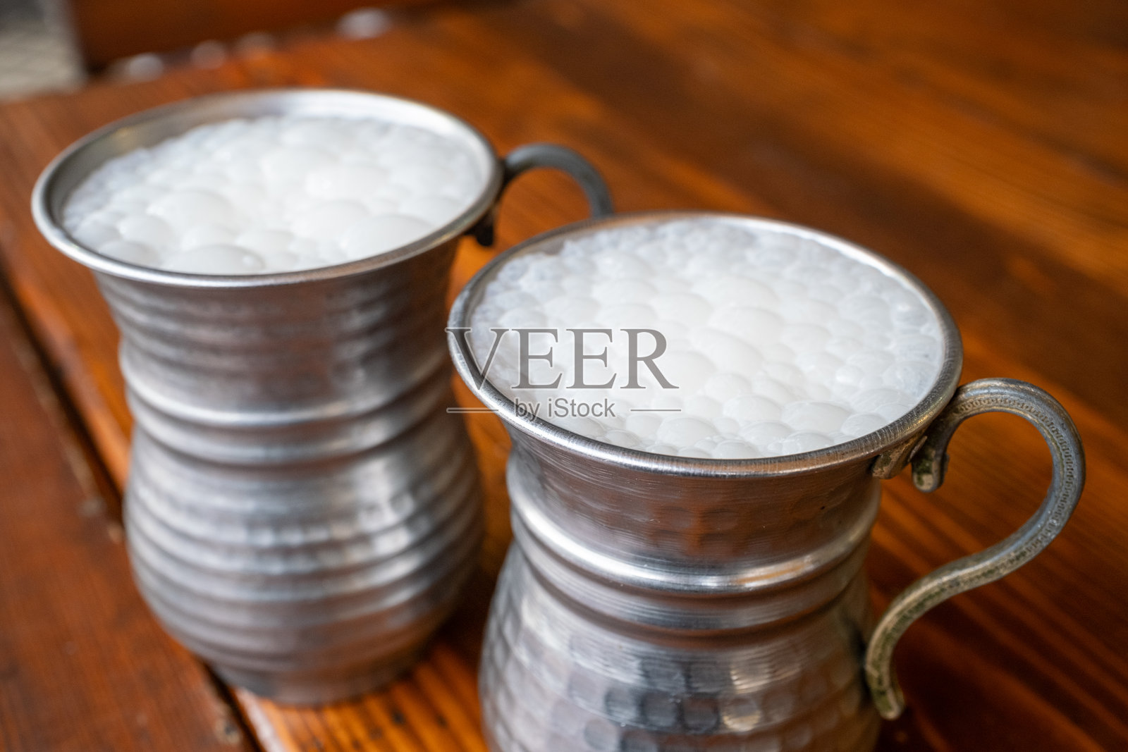 灰色传统金属杯中的土耳其酸奶饮料照片摄影图片