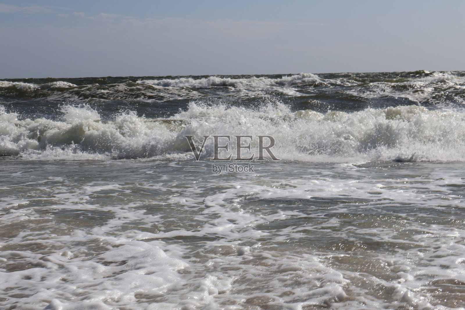 汹涌的海浪创造出动感十足的海景,白色的泡沫和在晴朗蓝天下闪烁的水面,唤起了自然的美丽与力量。照片摄影图片