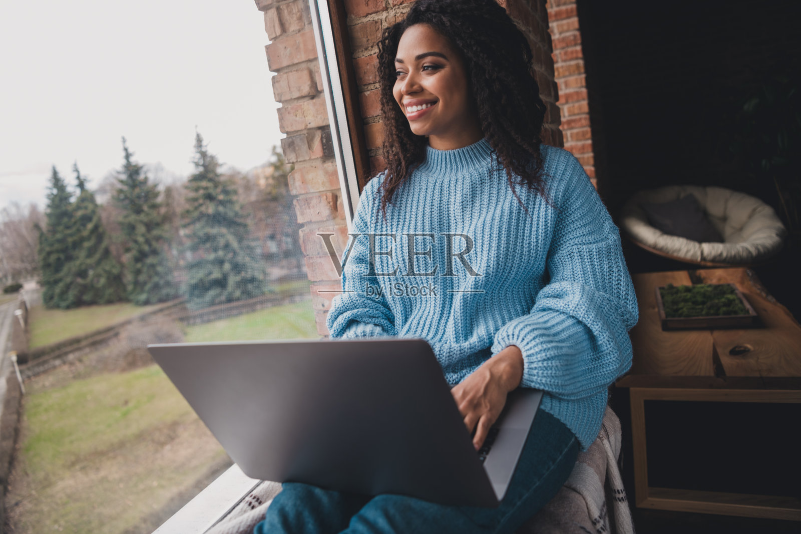 年轻女性在窗边穿着时尚毛衣,享受轻松的周末时光照片摄影图片