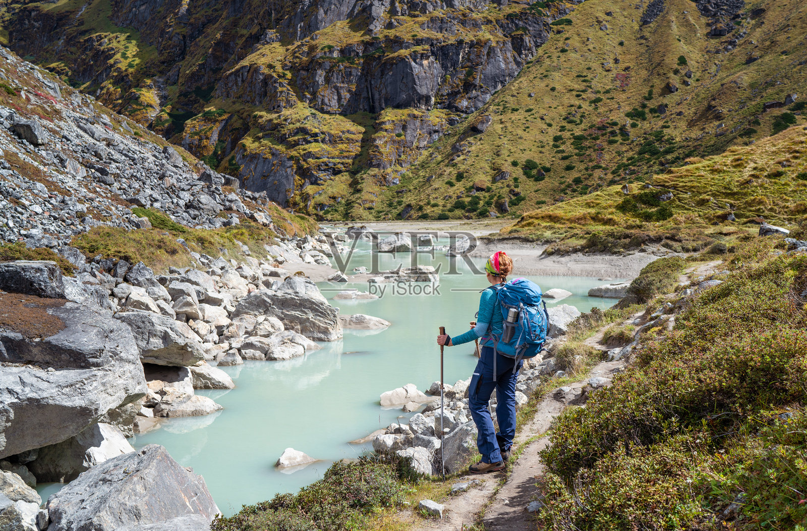 女性徒步旅行者穿着运动风格,背着背包,在梅拉峰攀登路线附近的冰川河流中享受,靠近海拔约4350米的萨巴伊措冰川湖。马卡鲁-巴伦国家公园,尼泊尔。照片摄影图片