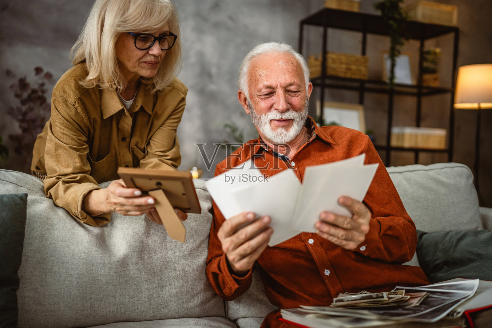 老年丈夫翻看家庭照片相册,女人则手持相框。照片摄影图片