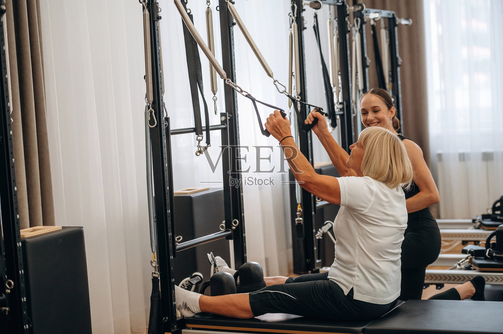 使用训练器材。女性教练正在帮助老年女性锻炼。照片摄影图片