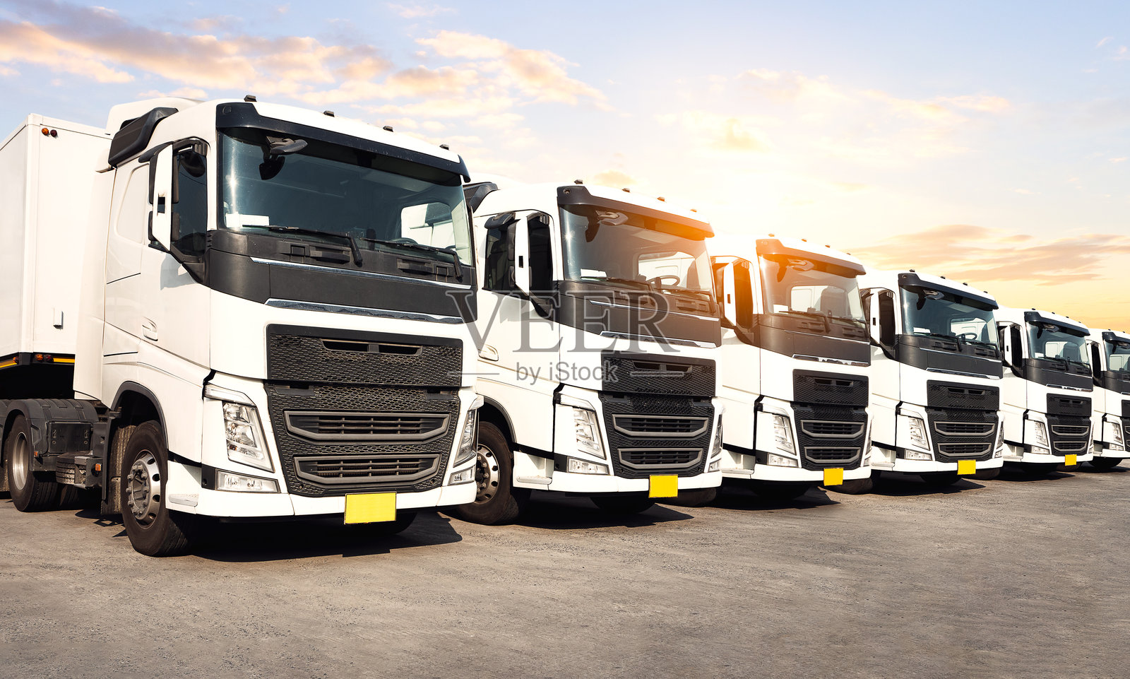 停在停车场的半挂车与夕阳天空。货物集装箱运输。经济商业道路运输。进出口。卡车运输。柴油货车。货运物流运输。照片摄影图片