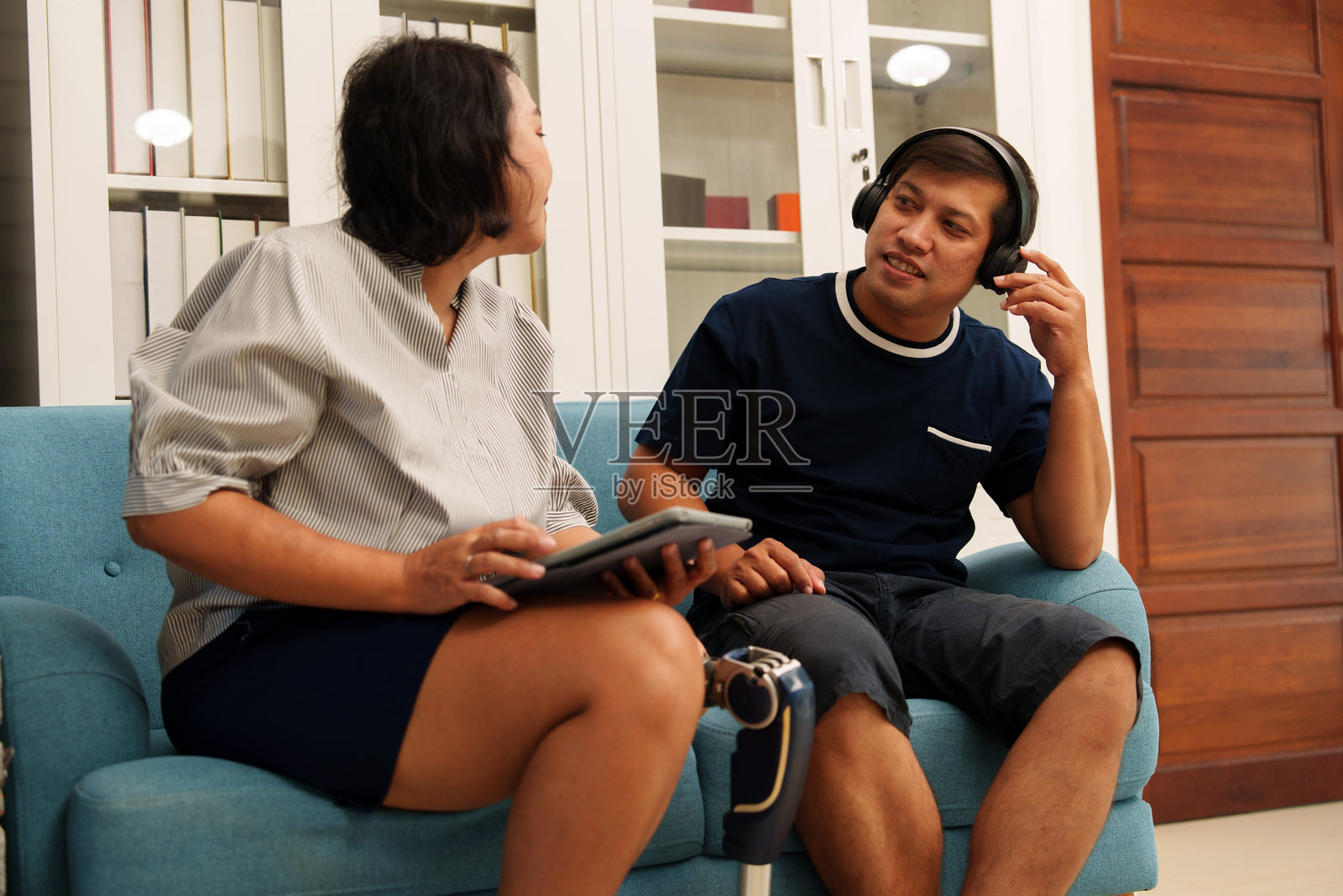 一对情侣正在愉快地讨论在线业务,女友的腿部残疾。照片摄影图片