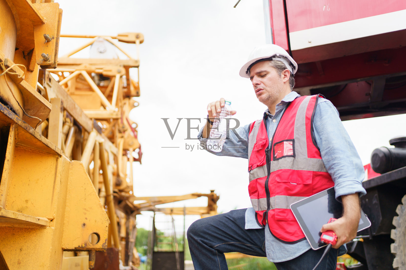口渴且疲惫的工人坐在地板上。照片摄影图片