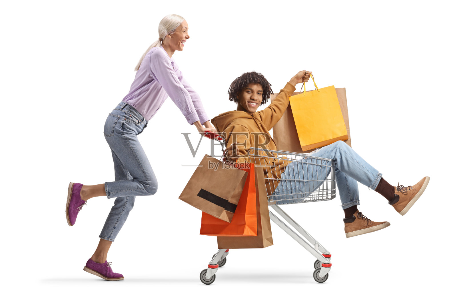 白人女性推着一位非裔美国男性,手里提着购物袋,坐在购物车里。照片摄影图片