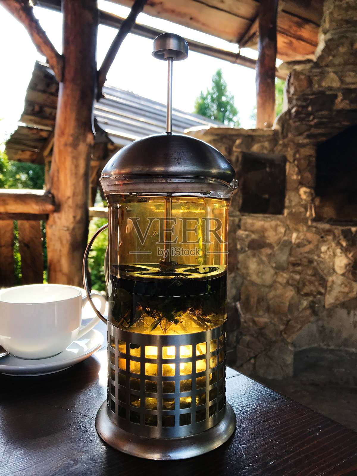 舒适的户外环境,配有法式压滤咖啡壶和白色茶杯照片摄影图片