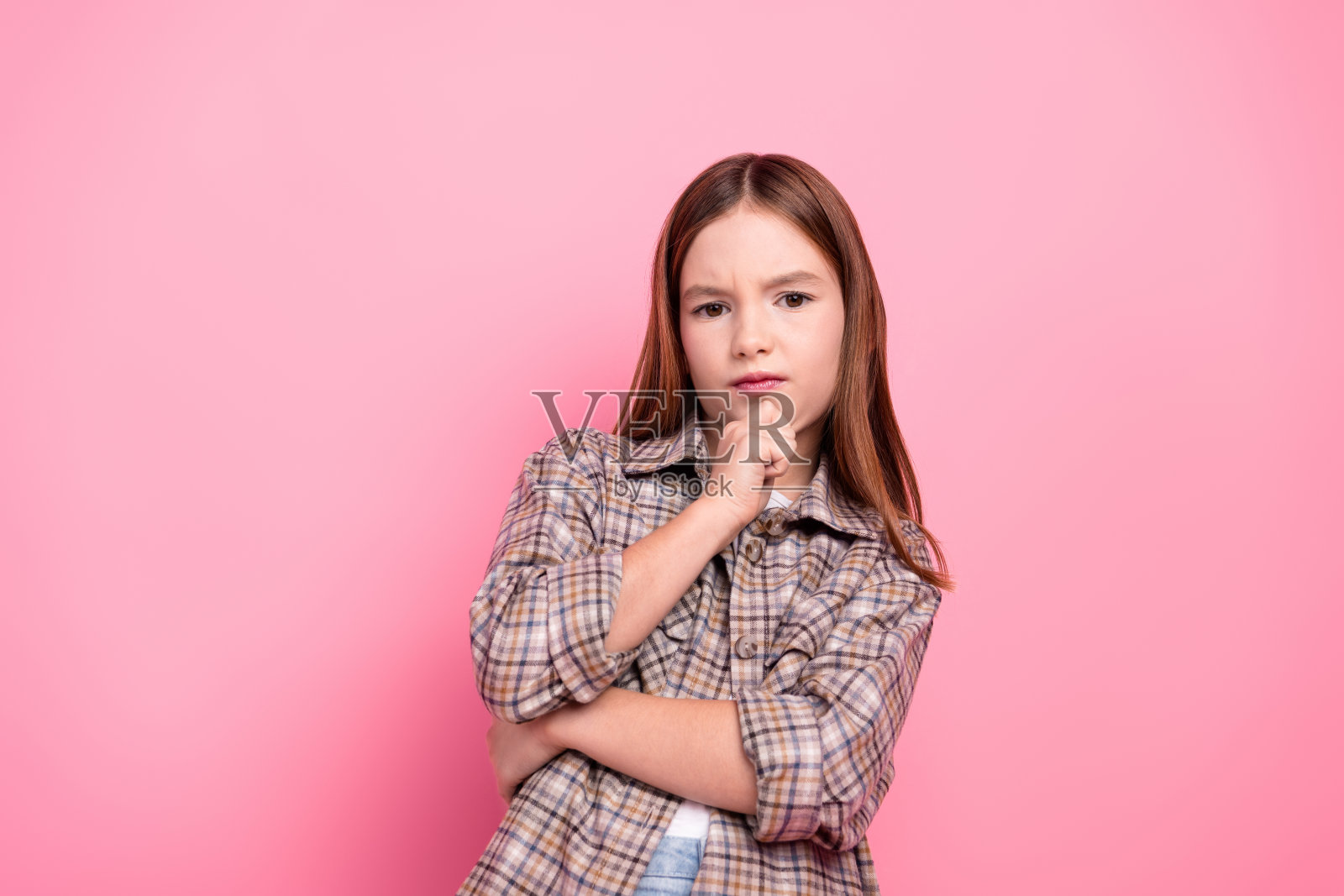 穿着格子衬衫的少女在粉色背景前深思熟虑地摆姿势照片摄影图片