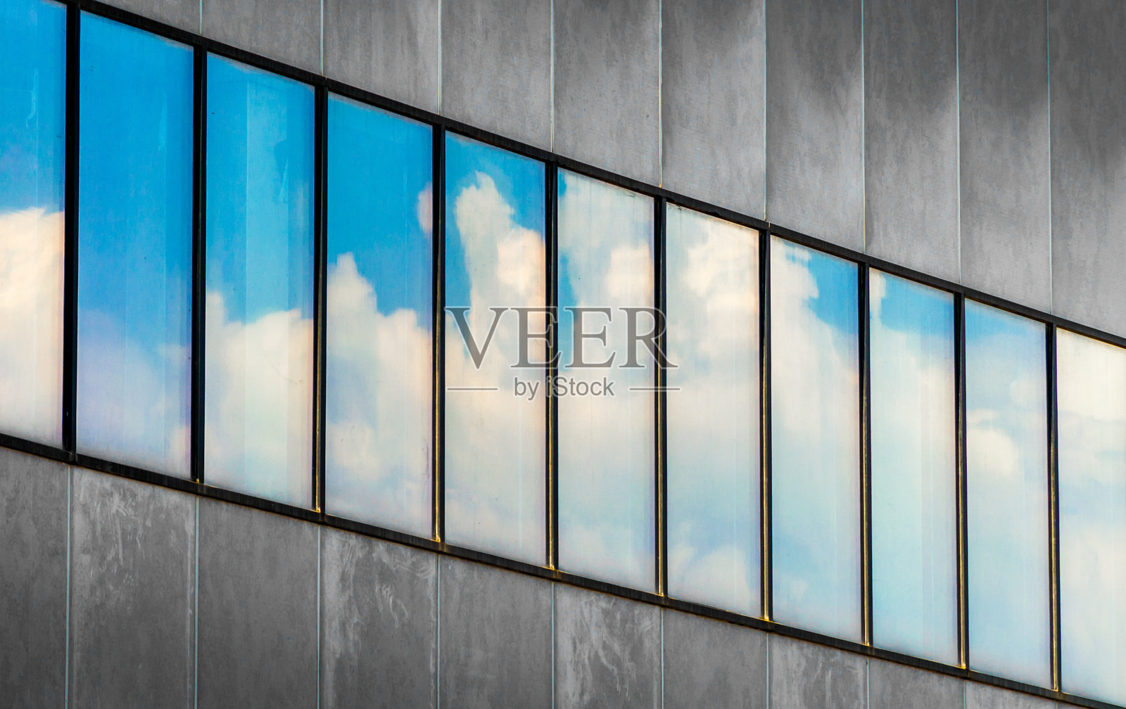 灰色混凝土建筑窗户中映射出的蓝天和白云的倒影照片摄影图片