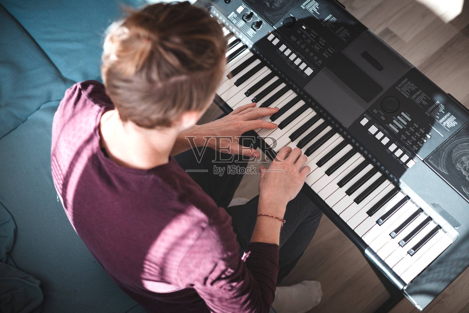 阳光明媚的房间内,一个人正在演奏电子键盘的俯视图,突显出专注与创造力的瞬间,柔和的自然光营造出轻松的氛围。音乐生活照片摄影图片