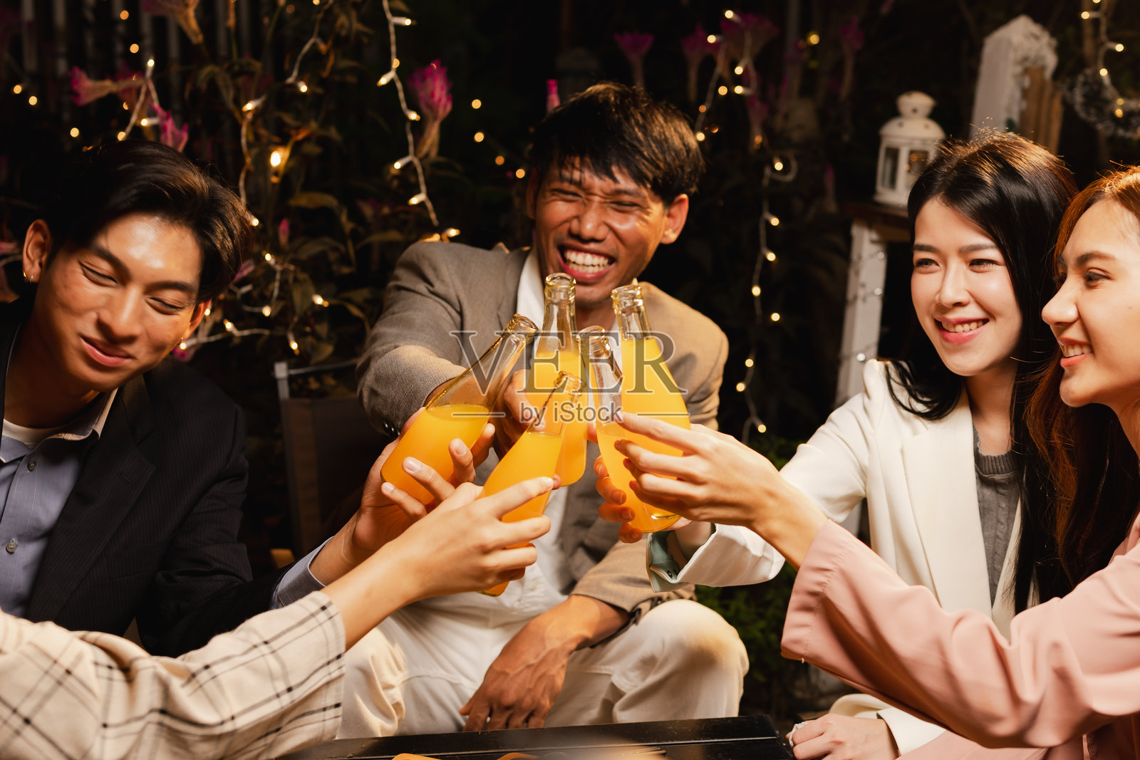 一群朋友在夜晚庆祝时碰杯。照片摄影图片