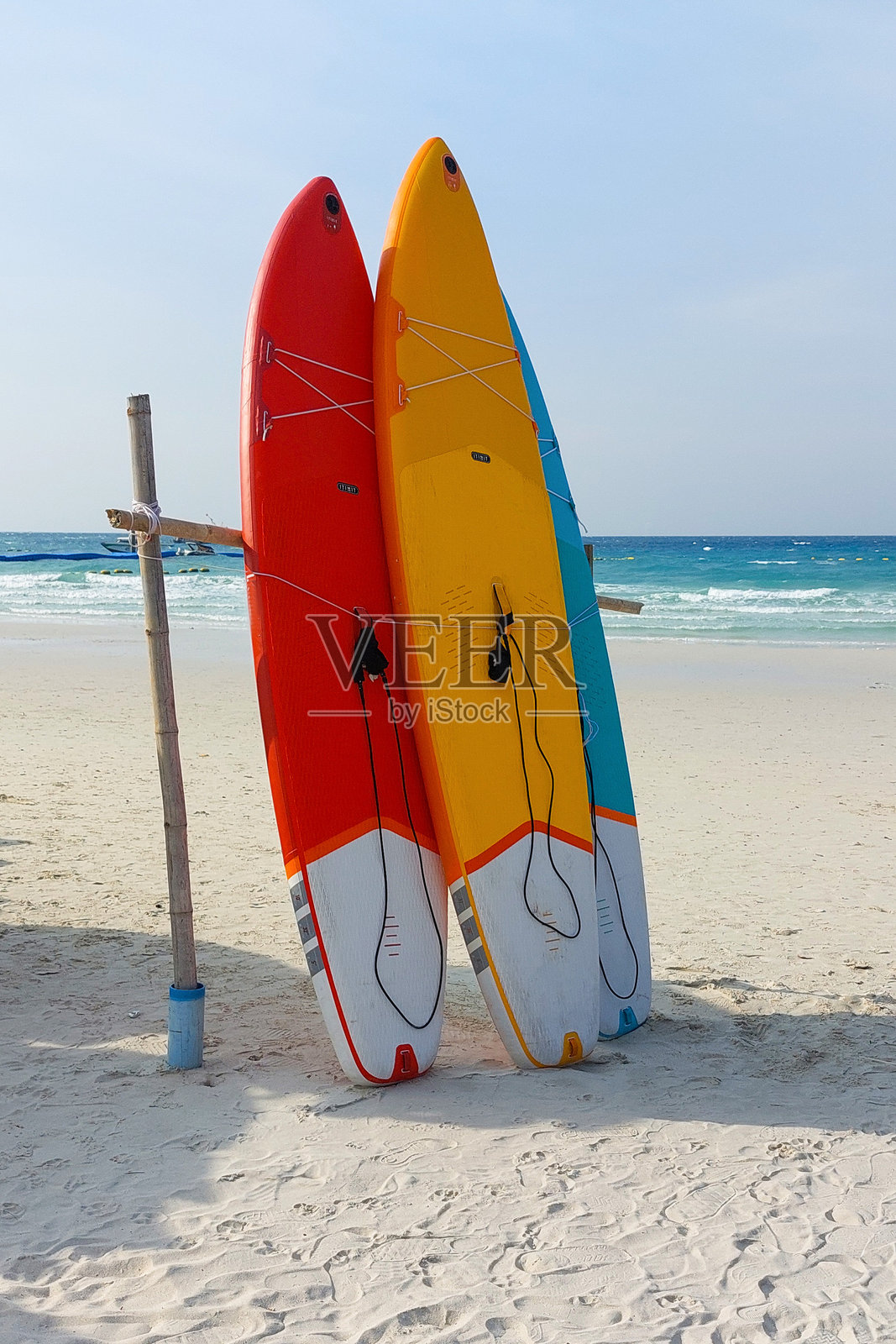 色彩鲜艳的冲浪板靠在木支架上,静静地等待着水上运动爱好者的到来。照片摄影图片