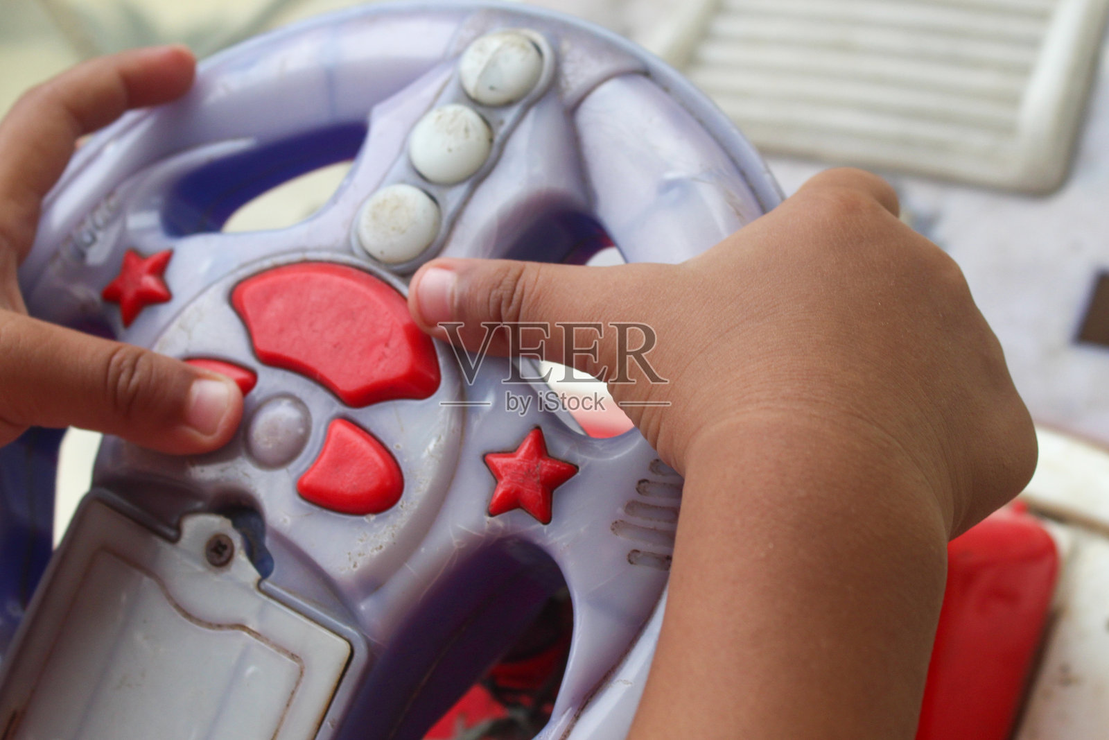 孩子的手握着玩具车方向盘的特写。孩子在玩玩具车。照片摄影图片