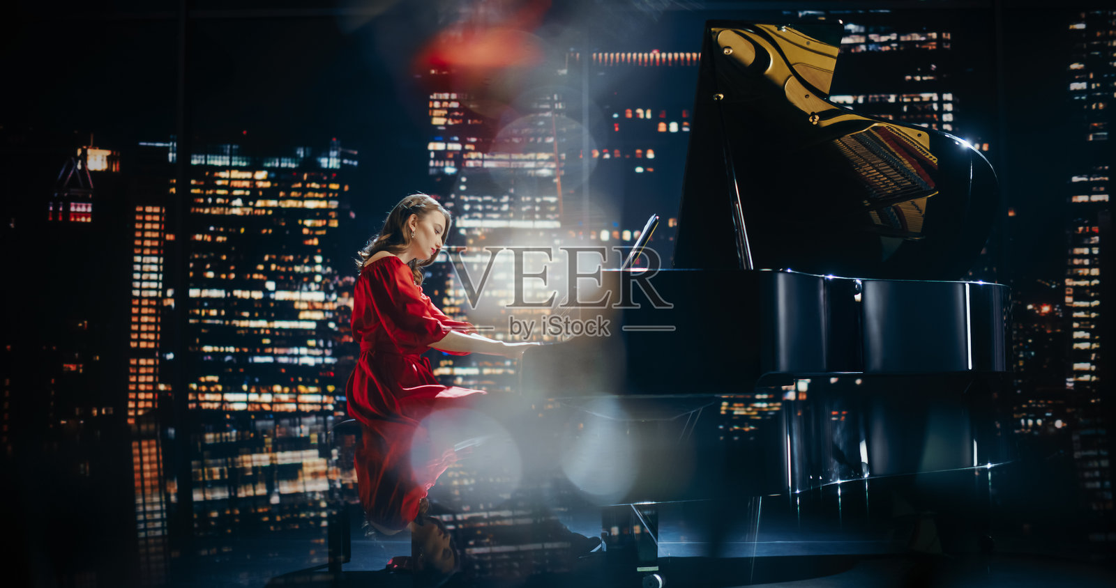 杰出的音乐艺术家在舞台上演出,她的手在大钢琴上轻松自如地移动。精致的观众观看着钢琴演奏者将每一首戏剧性和情感丰富的作品演绎得栩栩如生。照片摄影图片