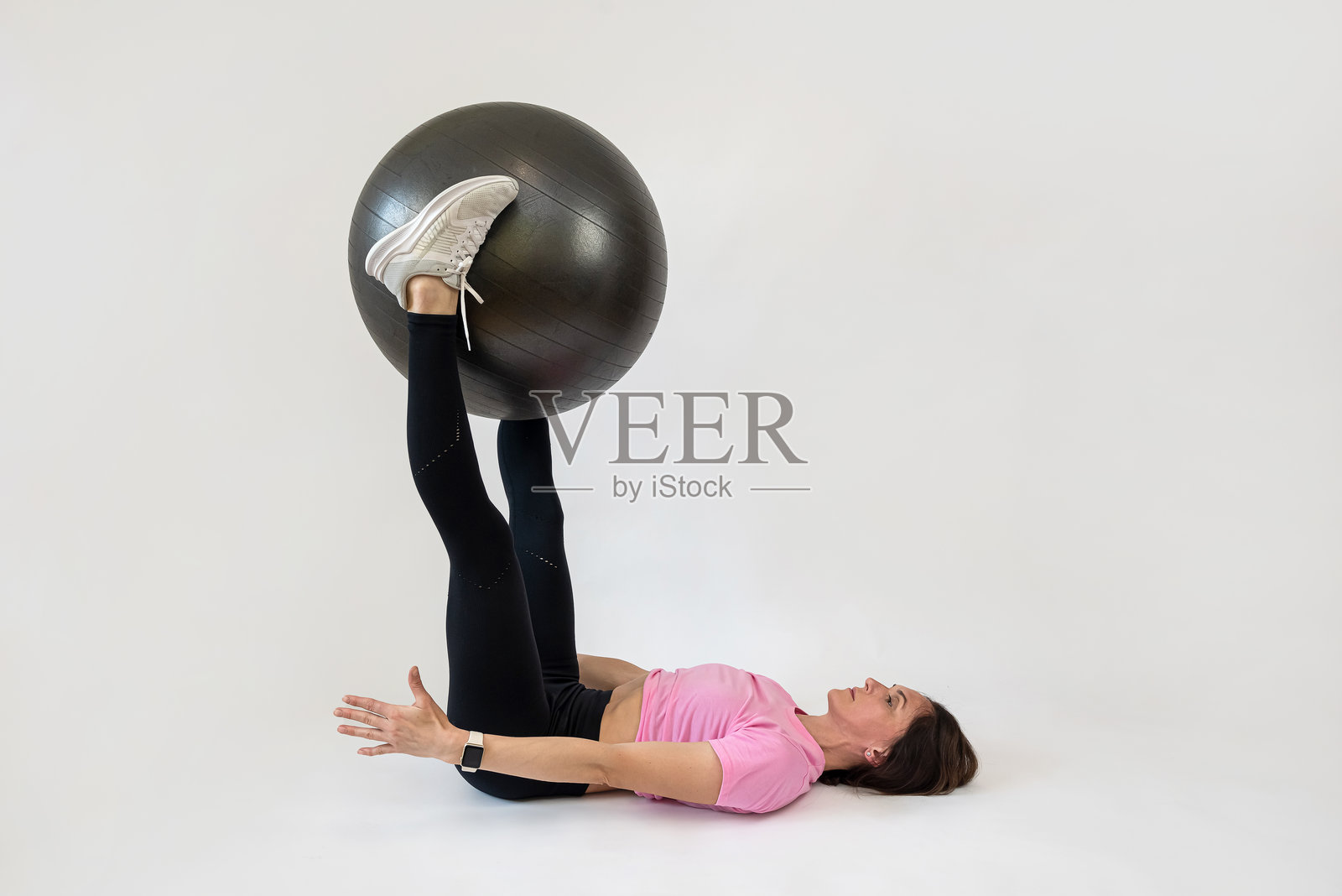 美丽的年轻健身教练在白色背景下使用健身球锻炼照片摄影图片